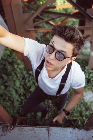 Guy in a shirt with suspenders among old metal structuresの写真素材