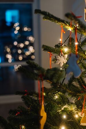 Christmas tree decorated with gingerbread cookies and garland, close-up view