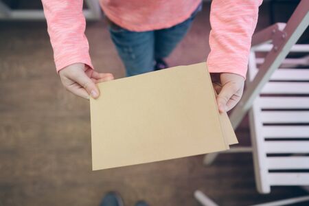 Little girl holding blank banner. Child showing paper sheet for sales advertisement, copy space. Commercial ad mockupの写真素材