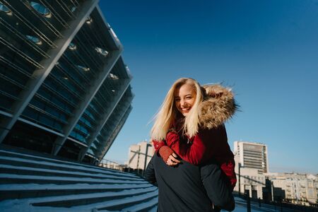 Guy on the shoulder is carrying the girl, winter outdoors.