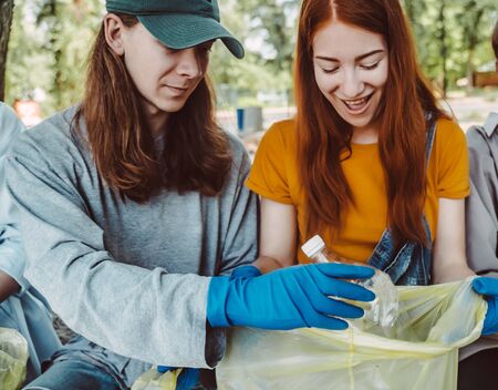 Man and Woman picking up trash from the park. They collecting the litter in garbage bagの写真素材