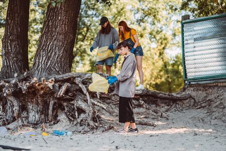 Group of activists friends collecting plastic waste on the beach. Environmental conservation.の写真素材