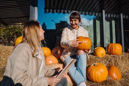 Girls have fun among pumpkins and haystacks on a city streetの写真素材