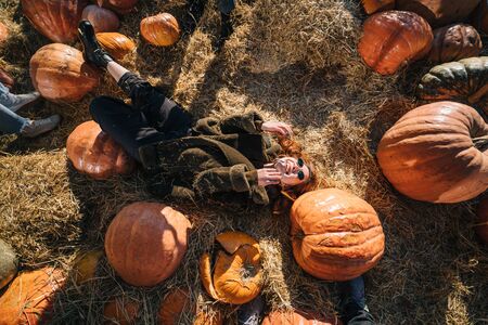 Young girl lie on haystacks among pumpkins.の写真素材