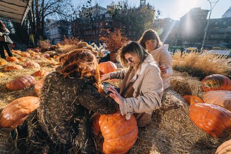 Young girls lie on haystacks among pumpkins.の写真素材