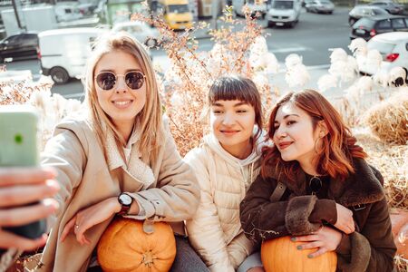 Beautiful girls sitting on haystacks take a selfieの写真素材