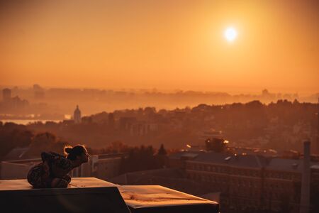 Woman doing yoga on the roof of a skyscraper in big city. Sunsetの写真素材