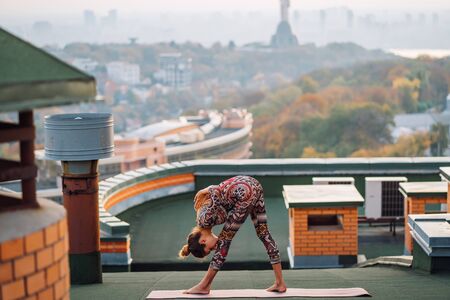Woman doing yoga on the roof in big city.