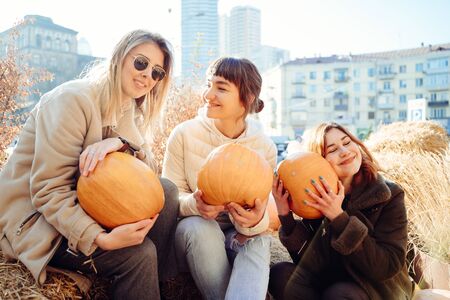 Girls holds pumpkins in hands on the background of the street.の写真素材