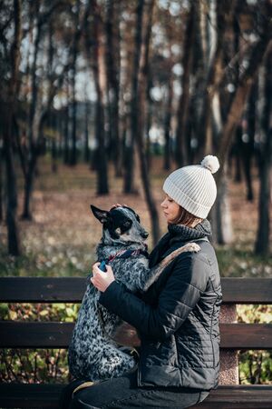 A girl is holding a mongrel dog in her arms. Caring for animals.の写真素材