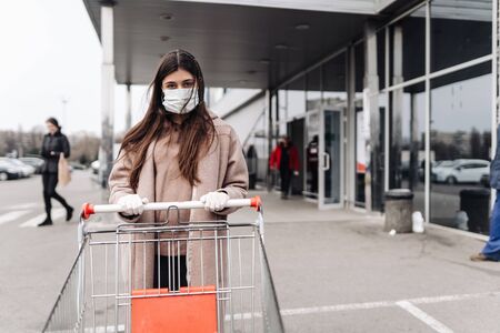 Young woman wearing protection face mask against coronavirus 2019-nCoV pushing a shopping cart.の写真素材