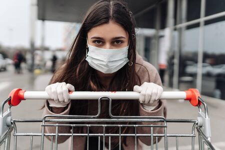 Young woman wearing protection face mask against coronavirus 2019-nCoV pushing a shopping cart.の写真素材
