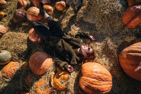 Young girl lie on haystacks among pumpkins.の写真素材