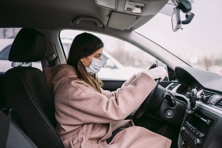 Young woman in a mask and gloves driving a car.の写真素材