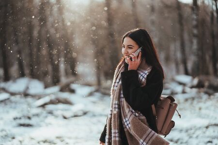 Woman talking on mobile phone. Smiling girl talking on mobile phone in cold winter day.の写真素材