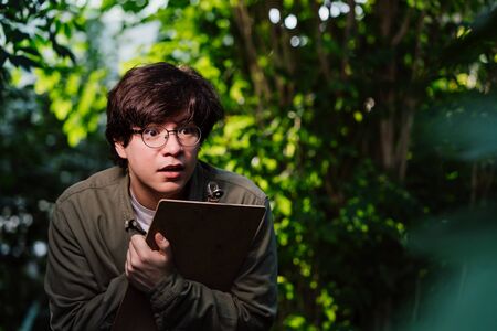 Male scientist hiding in the thicket. Nature protection concept.