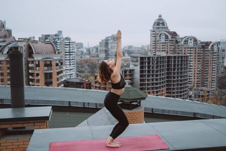 Woman practicing yoga on the mat on the roof and doing yoga exercisesの写真素材