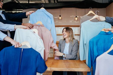 Young stylist looking through set of shirts for fashion shootingの写真素材