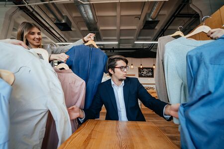 Young stylist looking through set of shirts for fashion shooting