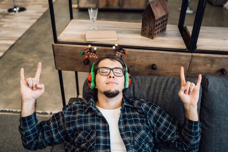 Happy man in headphones relaxing on the sofa at homeの写真素材