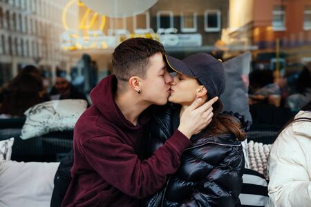 Guy and a girl are kissing at a table in a outdoor cafe.の写真素材