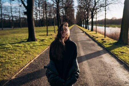 Portrait of a brunette girl having fun in a park in the rays of the bright sun.の写真素材