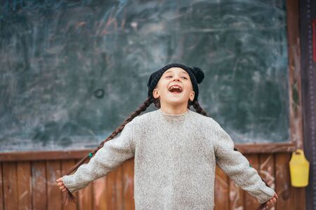 Little girl in a hat posing on the background of the school blackboardの写真素材