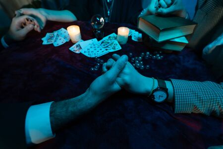 People hold hands of night at table with candles