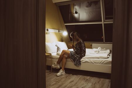 Young Woman Using Cell Smartphone . Happy Smiling Beautiful Girl on bed In Bedroom typing on mobile smartphoneの写真素材