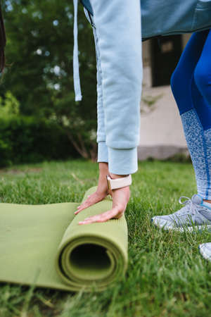 Close-up of woman folding roll fitness after working out in the park
