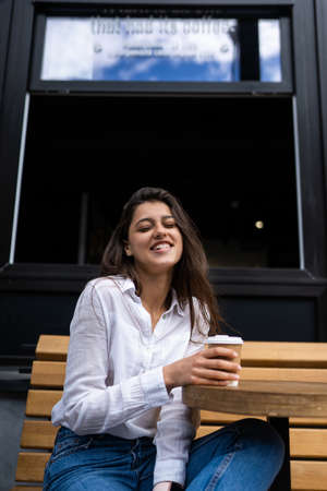 Beautiful young woman in street cafe drinks coffeeの写真素材