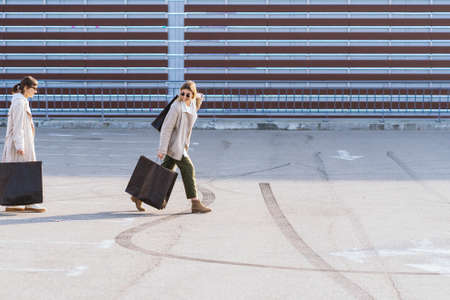 Young women with shopping bags walking on street.
