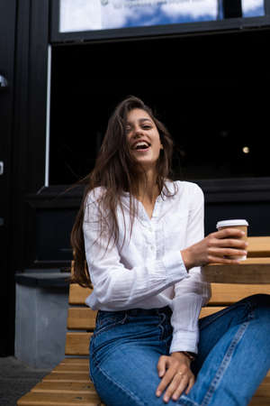 Beautiful young woman in street cafe drinks coffee