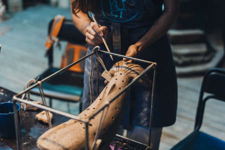 Close-up view of female hands gently handling a clay whale in workshop.の写真素材