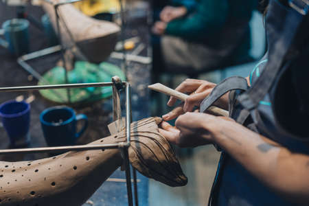 Close-up view of female hands gently handling a clay whale in workshop.