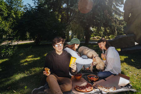 Company of beautiful young people and dog having an outdoor lunch.の写真素材