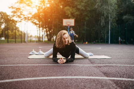 Young fit woman in sportswear trains outdoors on the playground.