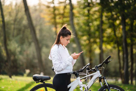 Young Caucasian woman resting in a park, uses a mobile phone.の写真素材