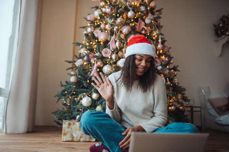 Female wearing santa hat while speaking with online friend on laptopの写真素材