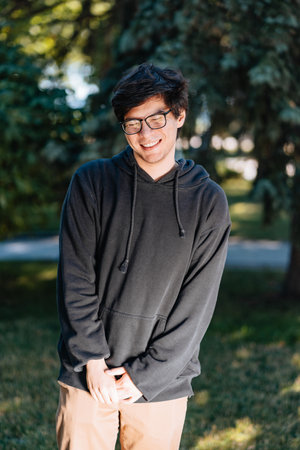 Portrait of happy young male student with glasses in casual outfit