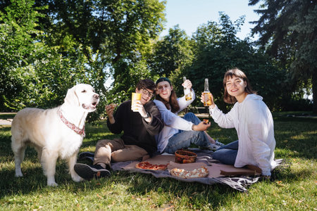 Company of beautiful young people and dog having an outdoor lunch.の写真素材