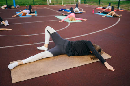 Young fit woman in sportswear trains outdoors on the playground.