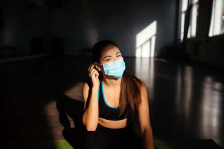 Portrait of fit woman putting on a protective face mask.の写真素材