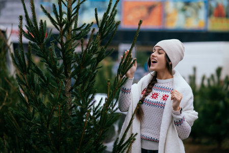 Woman with a white dog in her arms near a green Christmas treesの写真素材
