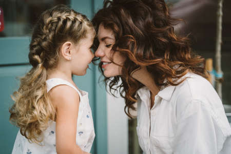 Portrait of little daughter kissing her beautiful happy motherの写真素材