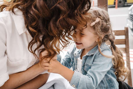 Mom and daughter eat french fries at an outdoor cafe