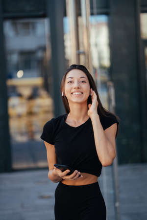 Portrait of a young brunette woman with headphones while walking