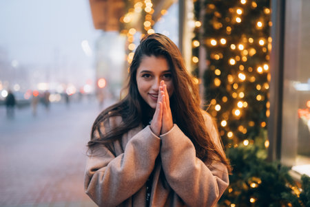 Woman by illuminated showcase on city street.の写真素材