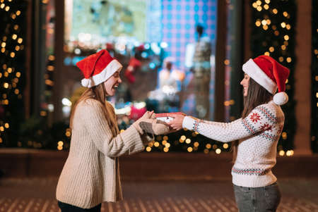 The girl gives a gift to her female friend on the street.の写真素材