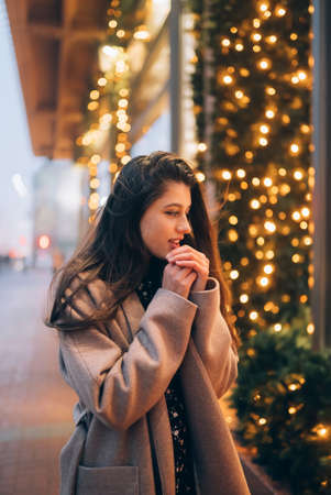 Woman by illuminated showcase on city street.の写真素材